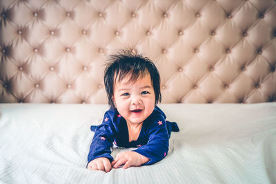 Portrait of cute girl sitting on bed at home