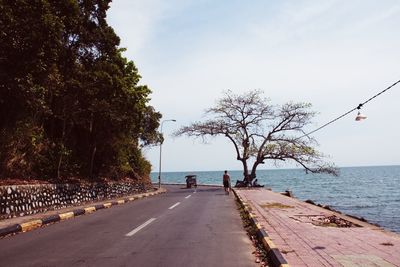 People on road by sea against sky