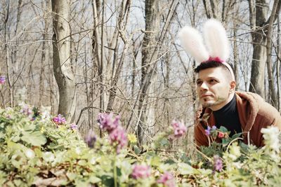 Young man wearing bunny ear headband in park