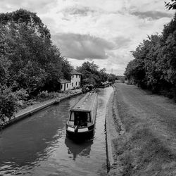 Scenic view of canal boat on river against sky