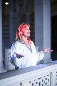 Smiling woman standing against railing at home