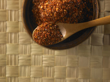 Directly above shot of chili flakes in wooden bowl on table