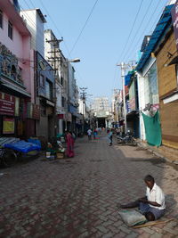 People sitting on street against buildings in city