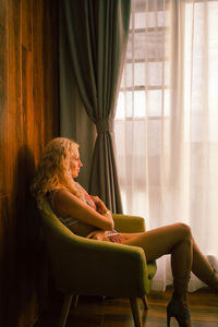 Side view of woman sitting on chair at home