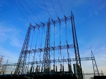 Low angle view of electricity pylon against blue sky