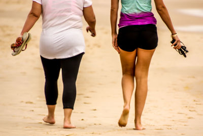 Low section of people walking on beach