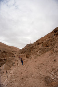 People on rock on land against sky