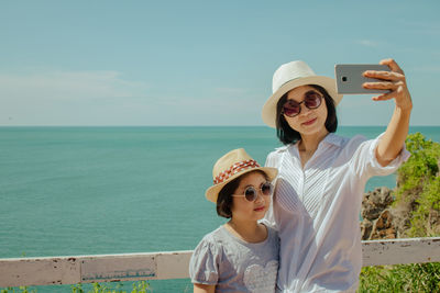 Mother and daughter taking selfie on sunny day