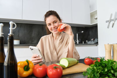 Portrait of young woman holding apple in kitchen