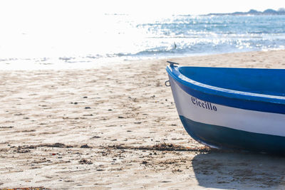 Boat moored on beach against sky