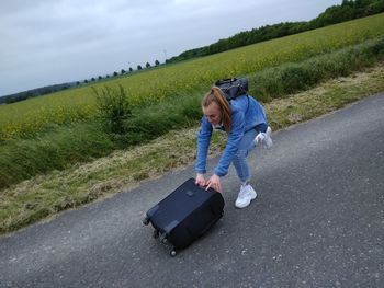 High angle view of teenage girl pushing luggage on road