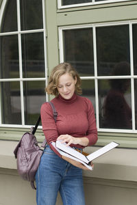 Young caucasian girl going back to college, school, standing with a notebooks