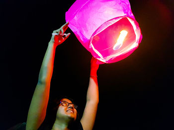 Portrait of young man with arms raised against black background