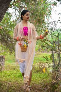 Young woman standing against plants