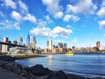 City at waterfront against cloudy sky