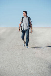 Young male with leg prosthesis walking against concrete building on street