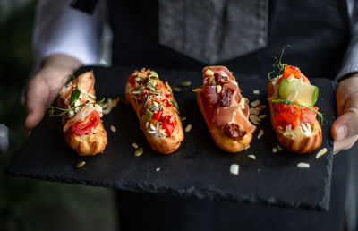 Eclairs with salmon, fresh vegetables and herbs, gourmet snacks.