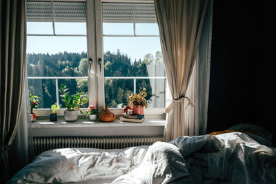 Sunlight streams into the bedroom, casting warm light across the unmade bed.