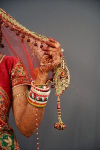 Midsection of bride in traditional clothing over gray background