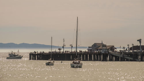 Boats moored at harbor against sky