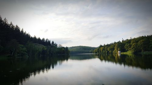 Scenic view of calm river with trees reflection against sky