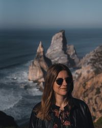 Portrait of young woman wearing sunglasses on rock