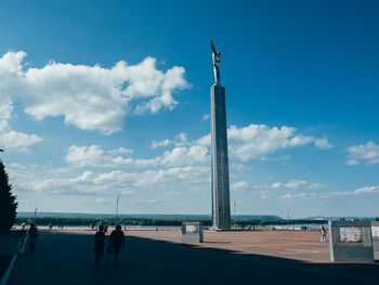 People in front of sculpture against sky