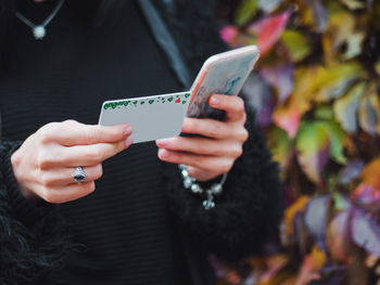 Close-up midsection of woman holding smart phone and card