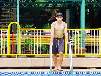 Portrait of shirtless man standing at poolside