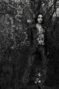 Portrait of woman standing by tree in forest