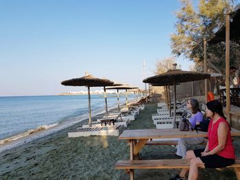 People on beach against clear sky