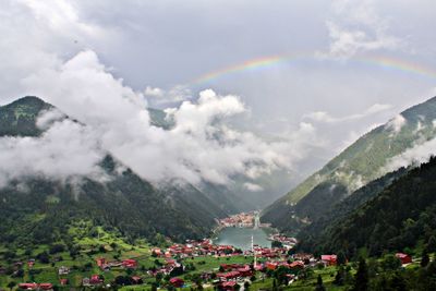 Scenic view of rainbow over mountain against cloudy sky