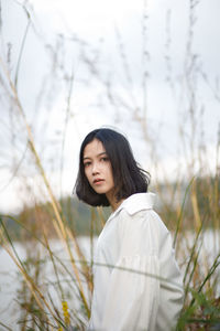 Portrait of young woman standing against trees