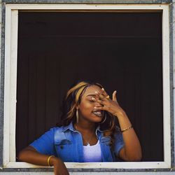 Young woman looking through window