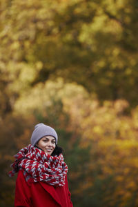 Portrait of young woman standing against trees