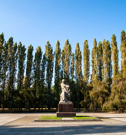 Statue and trees in park against sky