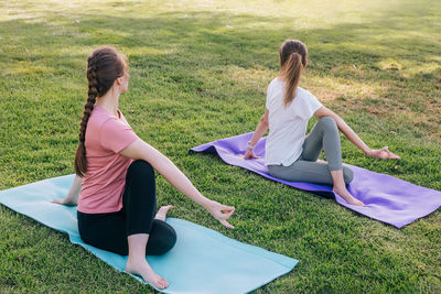 Two young women in the park doing yoga in the morning. exercising outdoors, healthy lifestyle