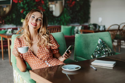 Young woman drinking coffee while sitting on table