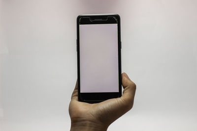 Close-up of hand holding smart phone against white background