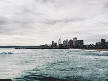 Scenic view of sea by buildings against sky