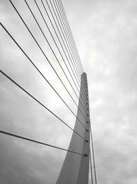 Low angle view of suspension bridge against cloudy sky