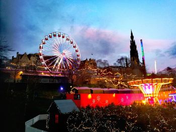 Illuminated ferris wheel against sky at night