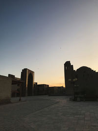 Silhouette buildings against clear sky at sunset