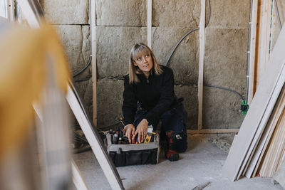 Female construction worker searching for tools in toolbox