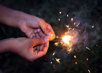 Close-up of person holding sparklers at night