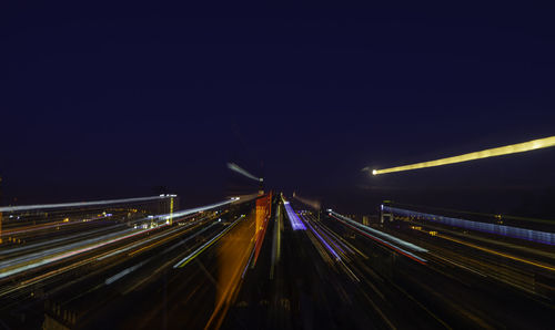 Light trails on highway in city against clear sky at night
