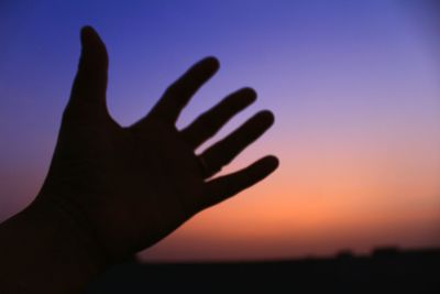Close-up of silhouette hand against sky during sunset