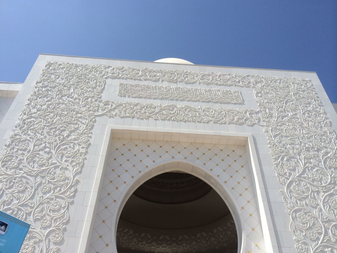 architecture, built structure, low angle view, building exterior, clear sky, text, arch, blue, communication, no people, white color, window, day, western script, outdoors, building, close-up, history, religion, copy space