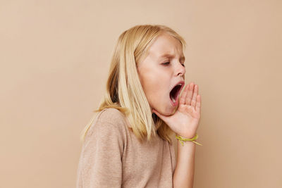 Young woman looking away against pink background