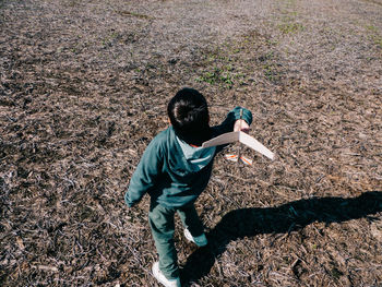 Rear view of boy with toy airplane standing on field